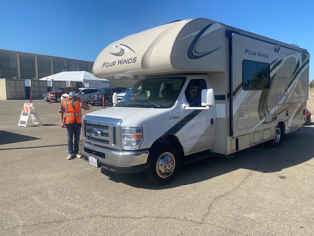 An RV arrives at the check-in site and is greeted by a staff member.