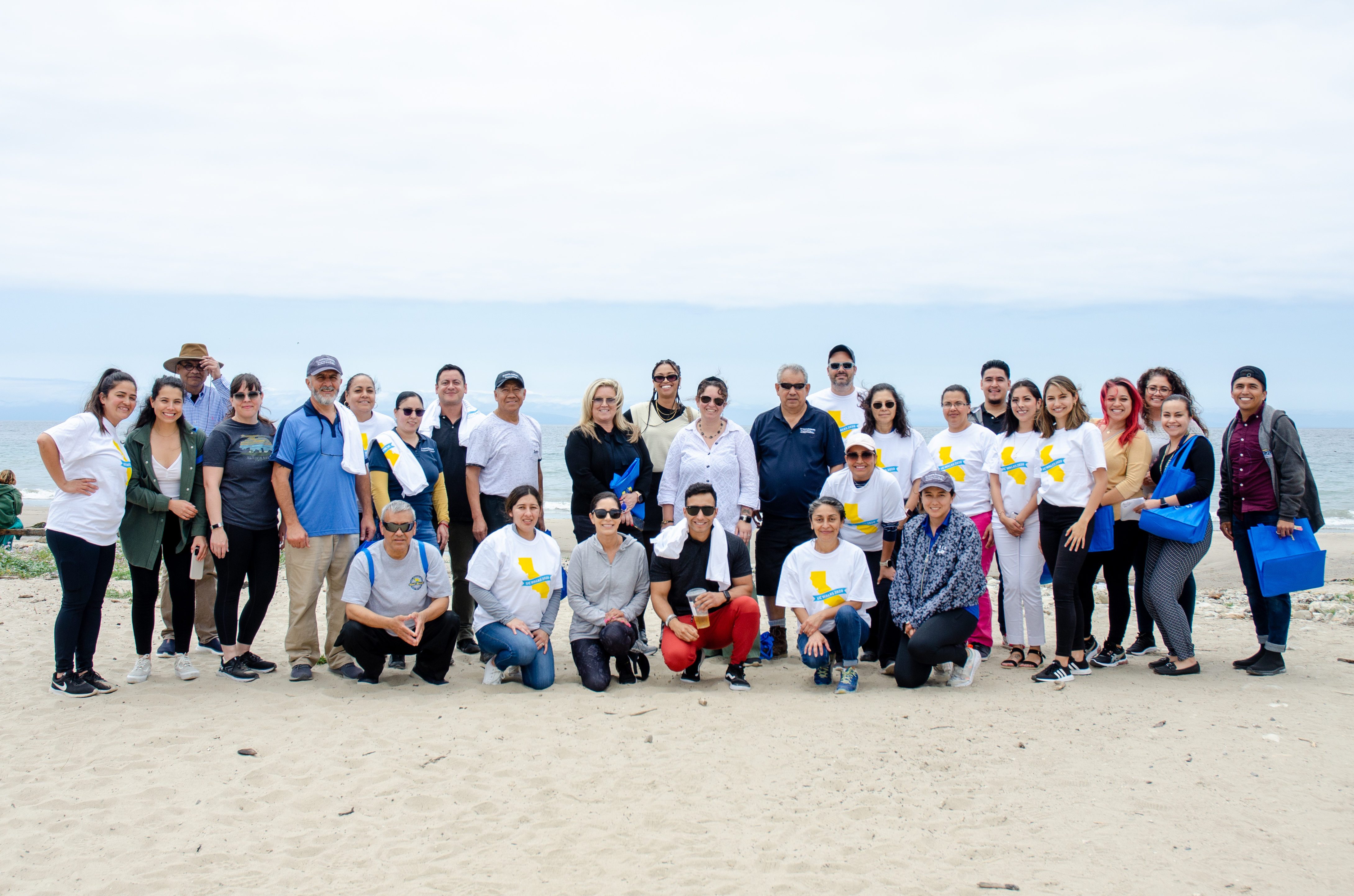Group photo of UCSB employees on the beach with the oean in the background