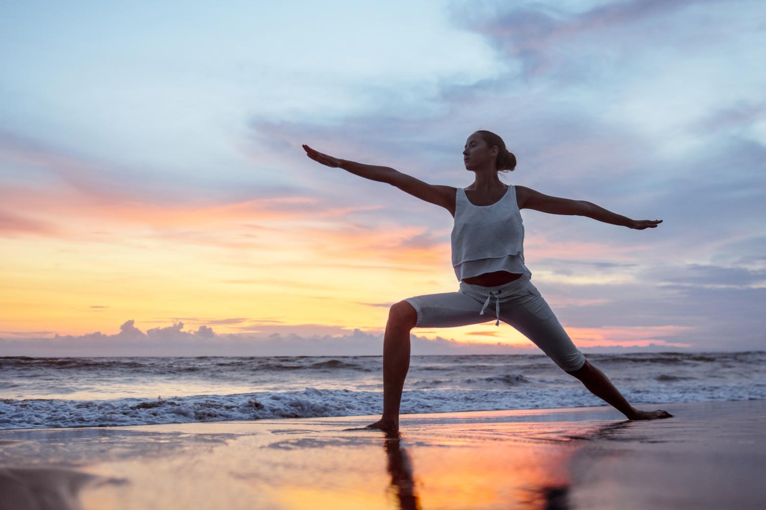 woman practicing yoga on the beach