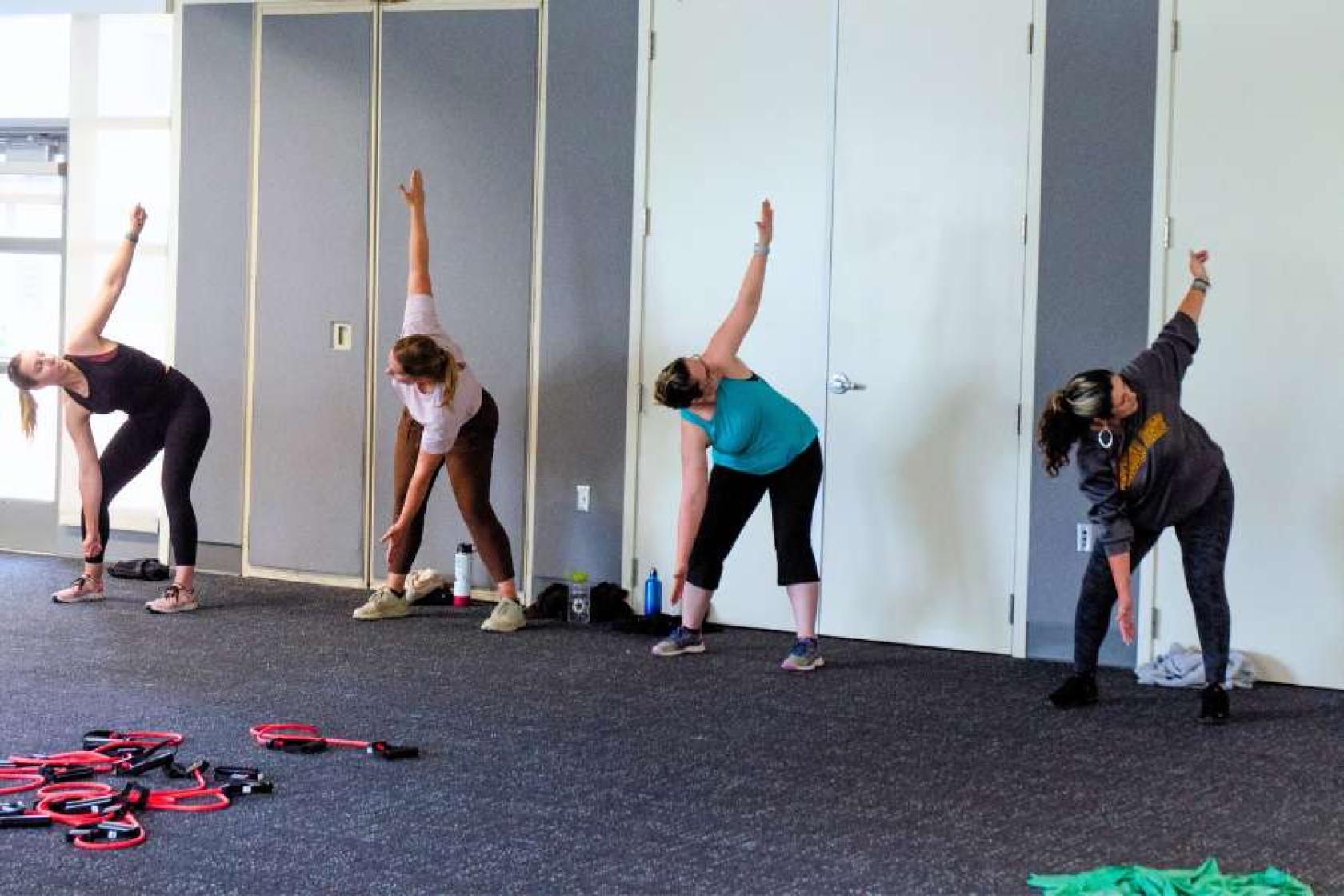 UCSB employees stretching with one hand in the air and the other hand reaching towards the ground