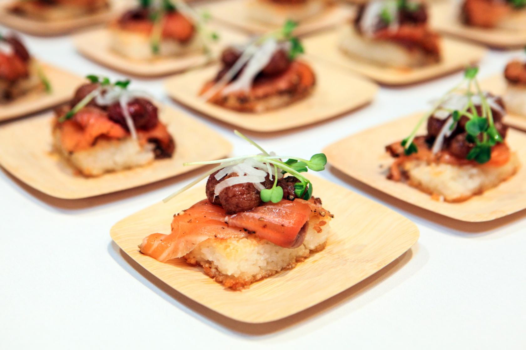 Five-Spice Roasted Grapes from California with a Ribbon of Szechuan Peppercorn-Crusted Salmon Gravlax, atop Crispy Sushi Rice, garnished with Kaiware and Pickled Daikon Matchsticks